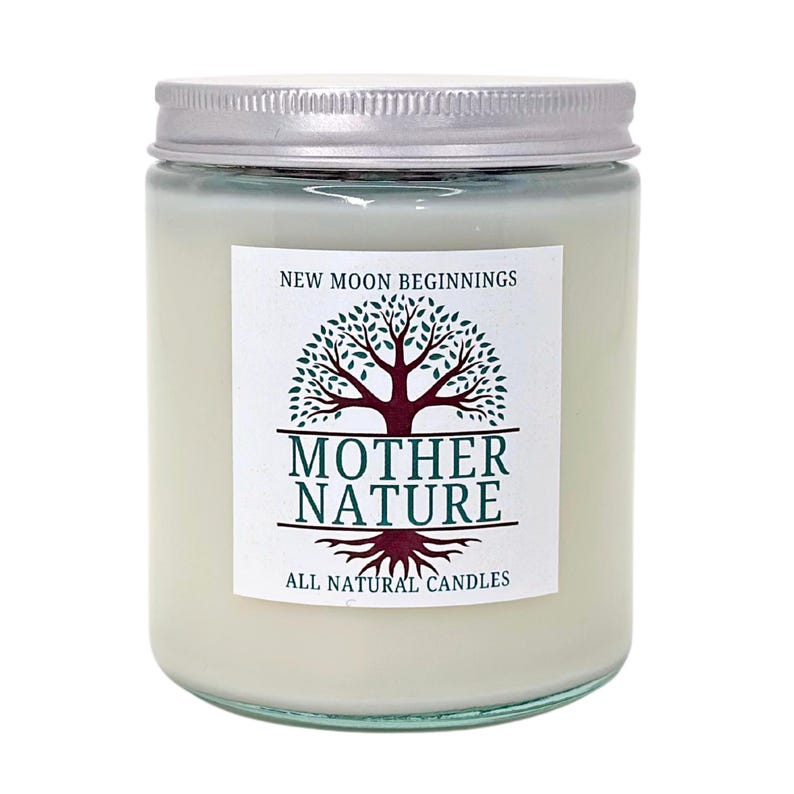 May include: A white candle jar with a silver lid. The label says "New Moon Beginnings" and features a green tree with brown roots and the text "Mother Nature All Natural Candles".