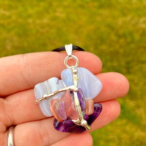 May include: A silver pendant necklace with a cluster of blue, pink, and purple gemstones. The stones are held together by silver wire and beads.