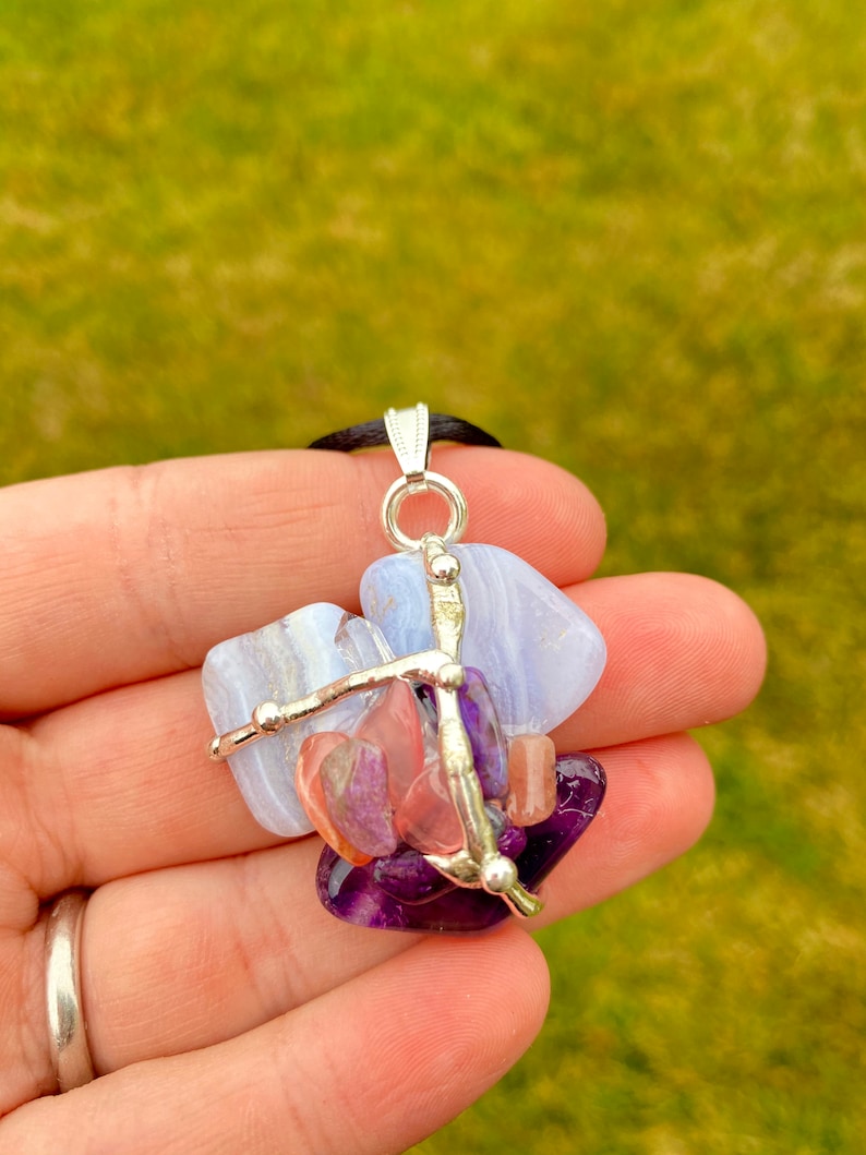 May include: A silver pendant necklace with a cluster of blue, pink, and purple gemstones. The stones are held together by silver wire and beads.
