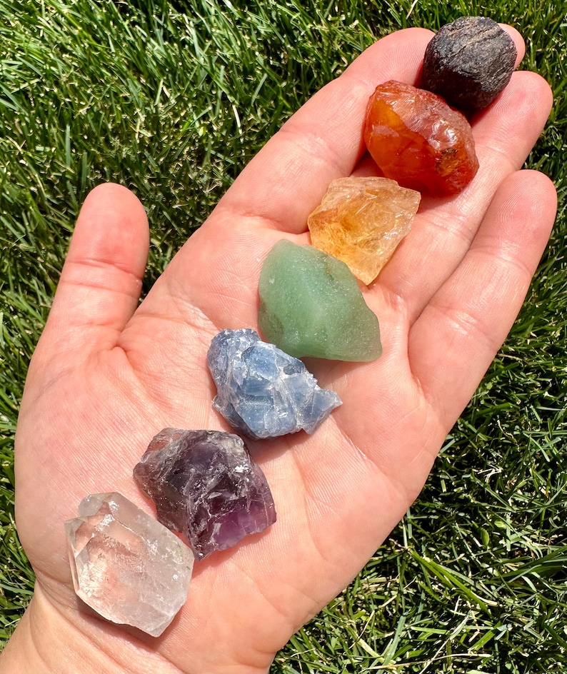May include: Seven chakra crystals in a rainbow colour order, from left to right: clear quartz, amethyst, blue lace agate, green aventurine, citrine, carnelian, and black obsidian.