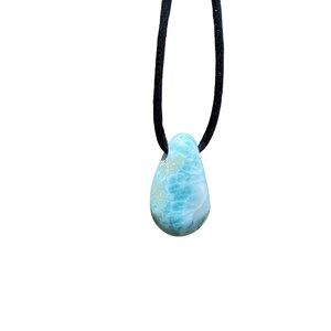 May include: A teardrop-shaped blue and green gemstone pendant on a black cord necklace.