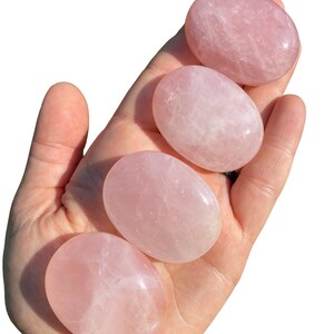 Pu&ograve; includere: Quattro pietre di quarzo rosa lisce, di forma ovale, in diverse tonalit&agrave; di rosa. Le pietre sono lucidate e hanno un aspetto traslucido.