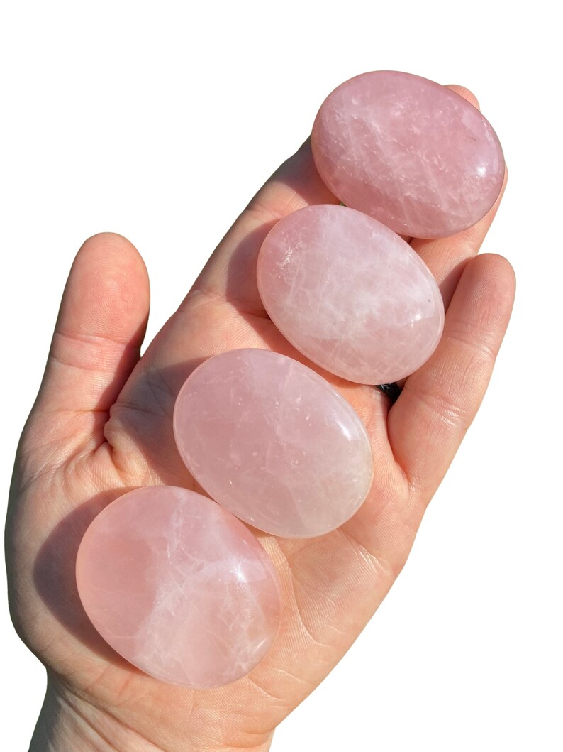 Pu&ograve; includere: Quattro pietre di quarzo rosa lisce, di forma ovale, in diverse tonalit&agrave; di rosa. Le pietre sono lucidate e hanno un aspetto traslucido.