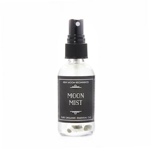 Puede incluir: Un frasco rociador de vidrio transparente con una tapa negra y una etiqueta negra. La etiqueta dice "MOON MIST" y "PURE ORGANIC ESSENTIAL OILS". La botella contiene peque&ntilde;as piedras transparentes. El texto "NEW MOON BEGINNINGS" est&aacute; en la parte superior de la etiqueta.