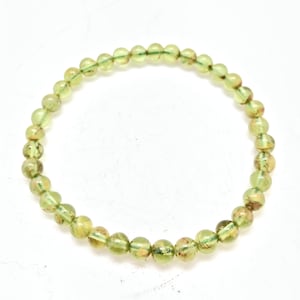 May include: A green gemstone bracelet with small round beads. The beads have a light green color with a subtle shimmer.