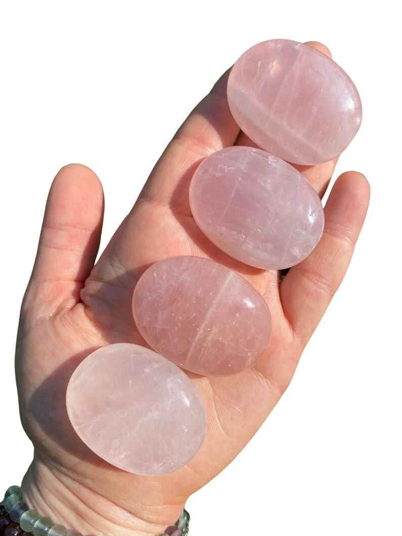 Pu&ograve; includere: Quattro pietre di quarzo rosa lisce, di forma ovale, in diverse tonalit&agrave; di rosa. Le pietre sono lucidate e hanno un aspetto traslucido.
