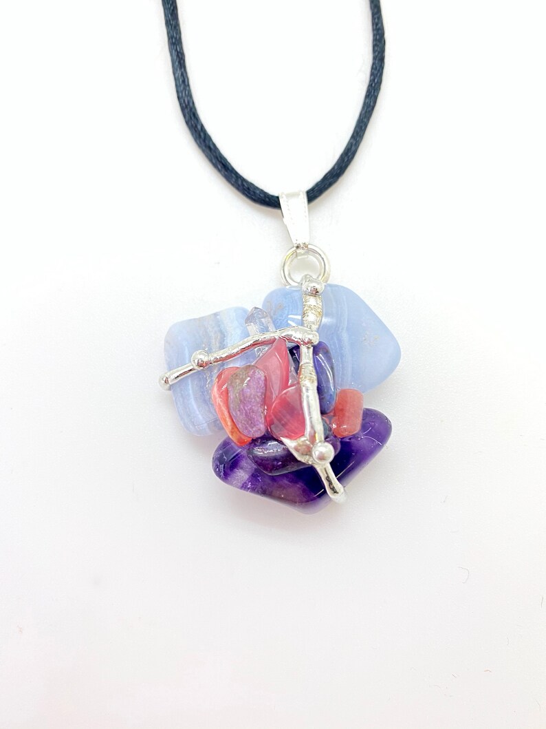 May include: A silver necklace with a pendant made of blue, purple, and pink stones. The stones are held together by silver wire.