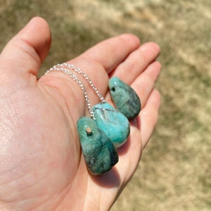 Puede incluir: Tres colgantes de piedra preciosa verde esmeralda en una cadena de plata. Los colgantes tienen forma de l&aacute;grima y tienen un acabado liso y pulido.