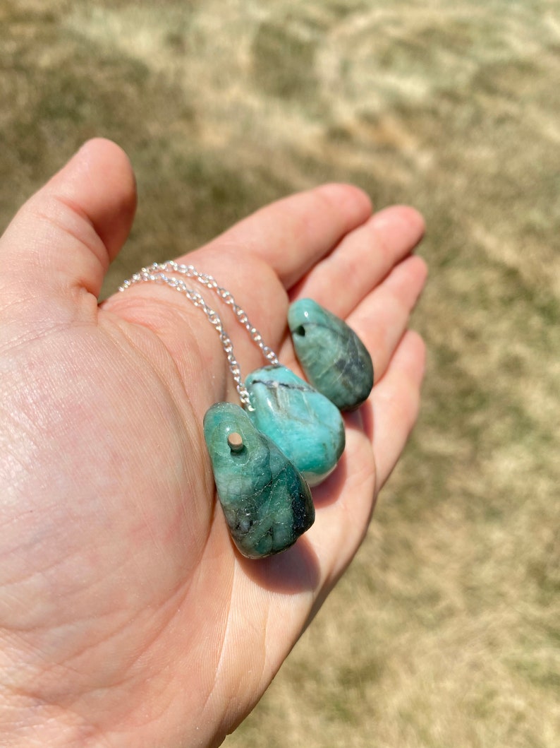 Puede incluir: Tres colgantes de piedra preciosa verde esmeralda en una cadena de plata. Los colgantes tienen forma de l&aacute;grima y tienen un acabado liso y pulido.