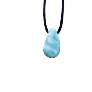 May include: A blue and green gemstone pendant on a black cord necklace.