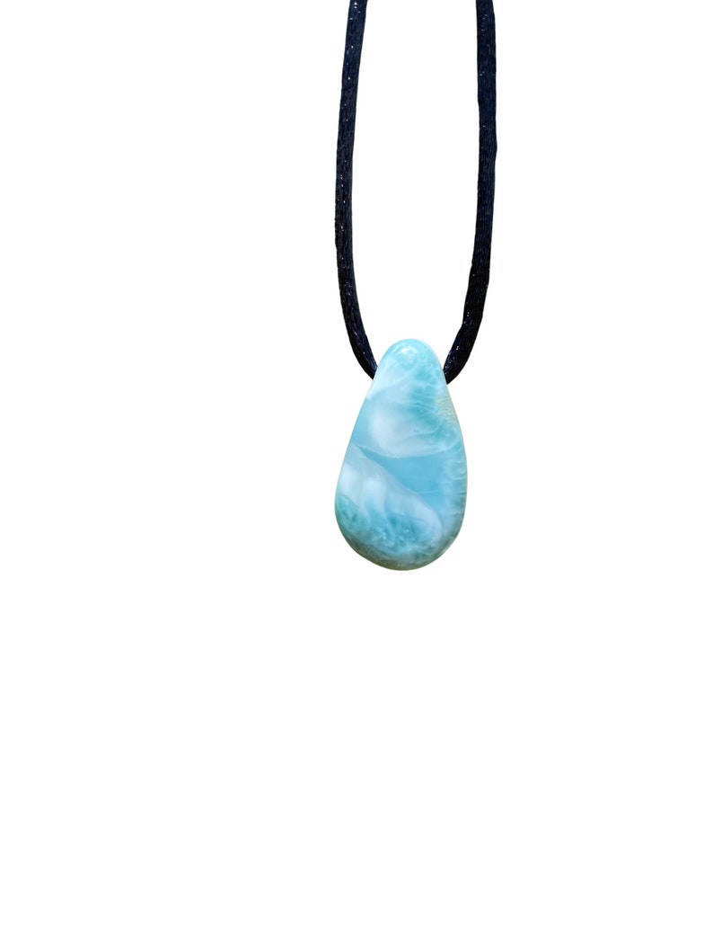 May include: A blue and green gemstone pendant on a black cord necklace.