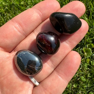 May include: Three tumbled stones, one black, one dark red, and one silver-grey.