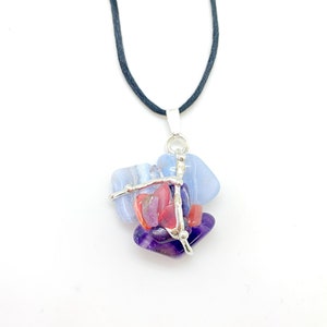 May include: A silver wire wrapped pendant necklace with blue, purple, and pink gemstones. The necklace is on a black cord.