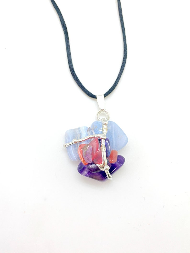 May include: A silver wire wrapped pendant necklace with blue, purple, and pink gemstones. The necklace is on a black cord.