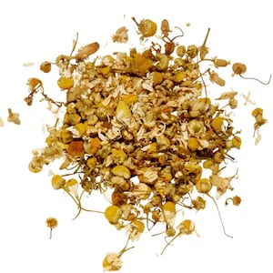 May include: A pile of dried chamomile flowers, featuring small, yellow, daisy-like blossoms and delicate, dried stems. The flowers are a mix of yellow and white, with a natural, organic appearance. The image is set against a clean white background.