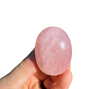 Pu&ograve; includere: Un cristallo di quarzo rosa liscio, di colore rosa pallido, a forma ovale. Il cristallo &egrave; lucido e ha un aspetto traslucido.