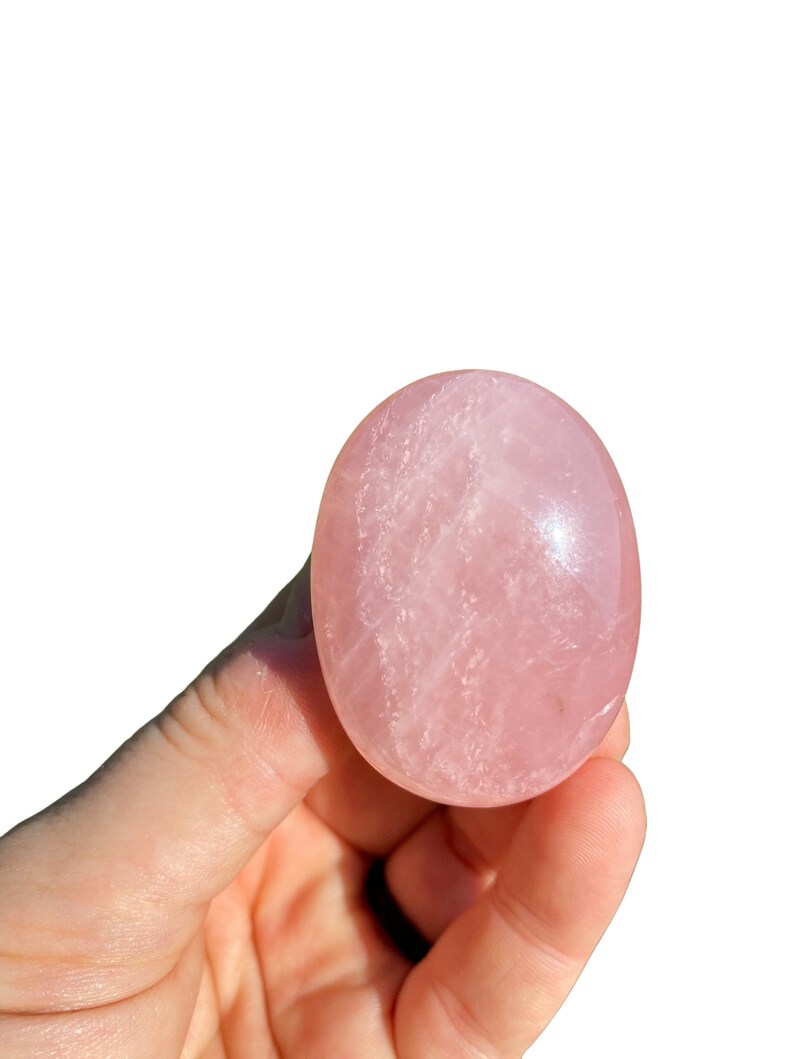 Pu&ograve; includere: Un cristallo di quarzo rosa liscio, di colore rosa pallido, a forma ovale. Il cristallo &egrave; lucido e ha un aspetto traslucido.