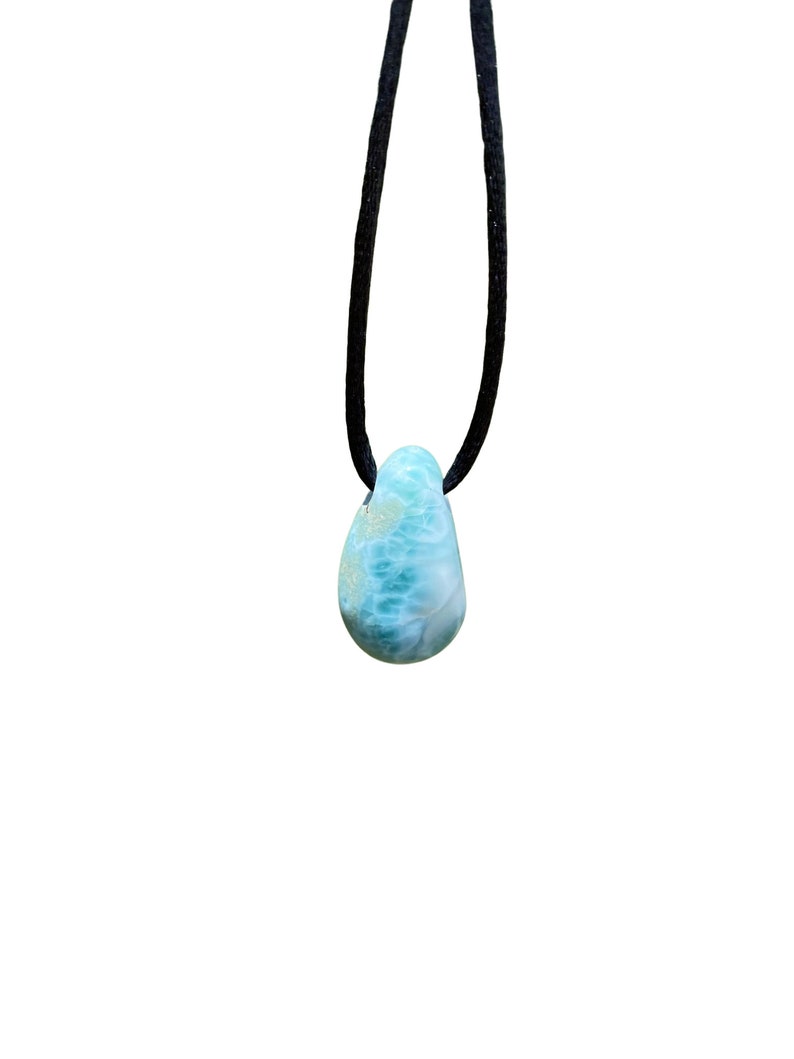 May include: A blue and green gemstone pendant on a black cord necklace.