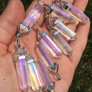 May include: A collection of eight iridescent clear quartz crystal pendants with silver-toned metal bails. The crystals are faceted and have a rainbow sheen.