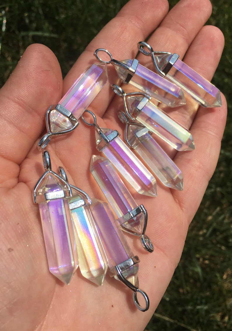May include: A collection of eight iridescent clear quartz crystal pendants with silver-toned metal bails. The crystals are faceted and have a rainbow sheen.