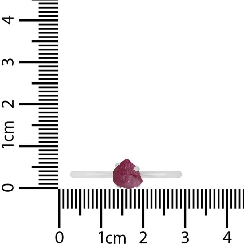 May include: A silver ring with a pink gemstone. The ring is shown on a ruler with a measurement of 1 cm.