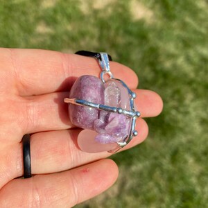 May include: A silver wire cage pendant with a pink and purple lepidolite crystal and a clear quartz crystal inside.
