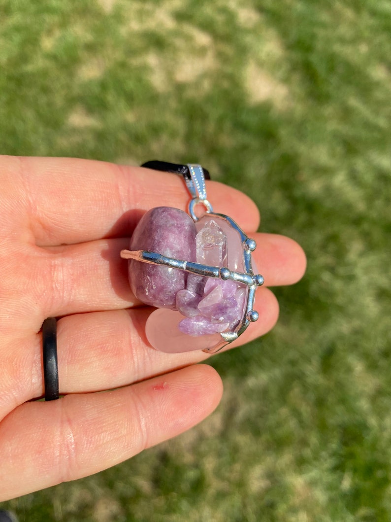 May include: A silver wire cage pendant with a pink and purple lepidolite crystal and a clear quartz crystal inside.