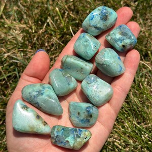 May include: A collection of ten tumbled blue and green chrysocolla stones. The stones are smooth and polished, with a variety of shapes and sizes.