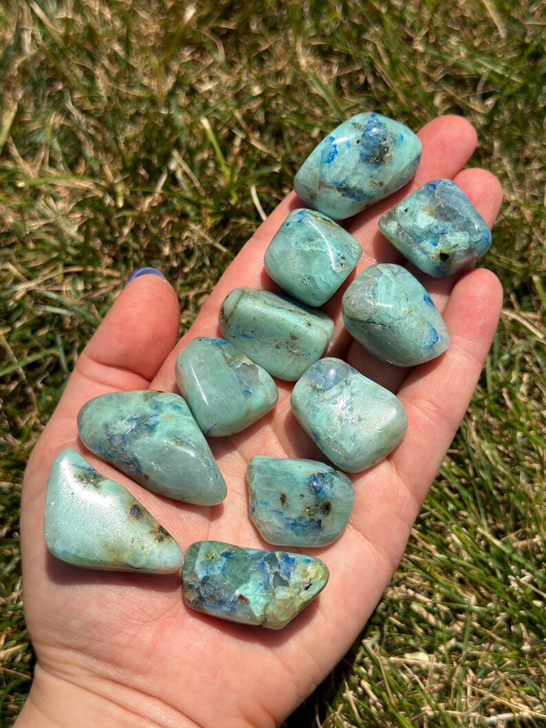May include: A collection of ten tumbled blue and green chrysocolla stones. The stones are smooth and polished, with a variety of shapes and sizes.