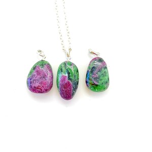 May include: Three green and pink gemstone pendants on silver chains. The stones are oval shaped and have a mottled appearance.
