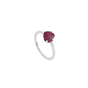 May include: A silver ring with a pink, rough-cut gemstone. The ring is marked "925" on the band.