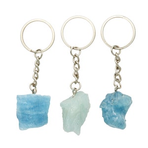 May include: Three silver keychains with different colored aquamarine stones attached. The stones are all rough and natural looking.