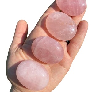 Pu&ograve; includere: Quattro pietre di quarzo rosa lisce e levigate di diverse dimensioni. Le pietre sono di colore rosa pallido e hanno un aspetto naturale leggermente nuvoloso.