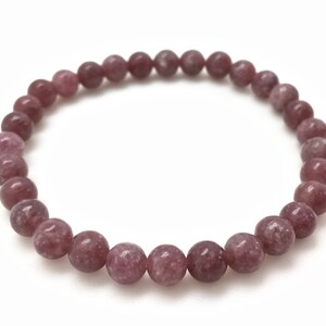 Puede incluir: Un brazalete de piedra de lepidolita rosa con cuentas redondas.
