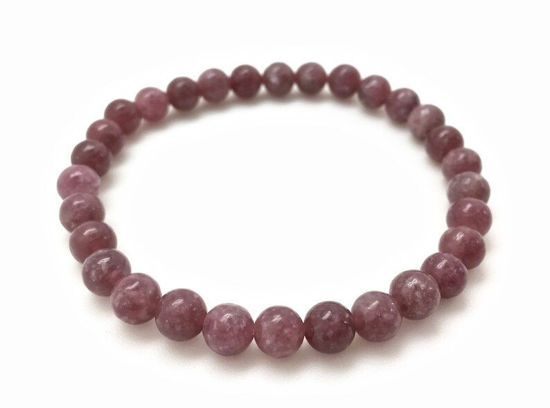 Puede incluir: Un brazalete de piedra de lepidolita rosa con cuentas redondas.