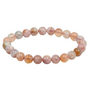 Puede incluir: Un brazalete de cuentas de ágata rosa y blanca con una banda elástica.