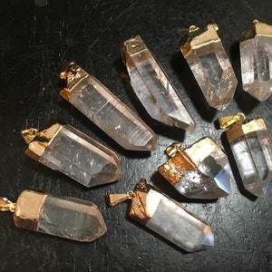 Puede incluir: Nueve colgantes de cristal de cuarzo transparente con tapas chapadas en oro. Los cristales son facetados y tienen una forma puntiaguda. Los colgantes son perfectos para la elaboraci&oacute;n de joyas o manualidades.