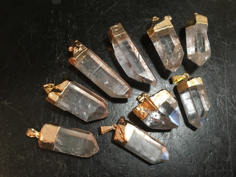 Puede incluir: Nueve colgantes de cristal de cuarzo transparente con tapas chapadas en oro. Los cristales son facetados y tienen una forma puntiaguda. Los colgantes son perfectos para la elaboraci&oacute;n de joyas o manualidades.
