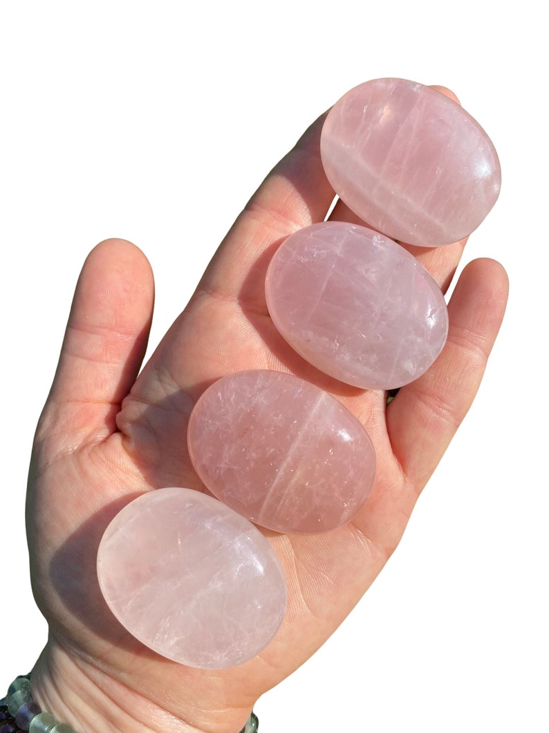 Pu&ograve; includere: Quattro pietre di quarzo rosa lisce, di forma ovale, di diverse dimensioni. Le pietre sono rosa pallido e traslucide, con striature visibili.