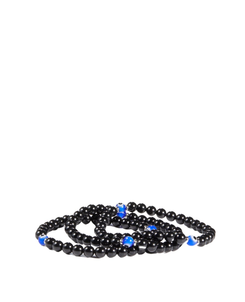 May include: Three black beaded bracelets with blue and silver accents. The bracelets are made of small, round, black beads and feature blue eye-shaped beads interspersed throughout. The bracelets are arranged in a layered style.