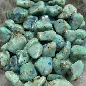 May include: A collection of tumbled blue green azurite stones. The stones are smooth and polished, with a variety of shapes and sizes.