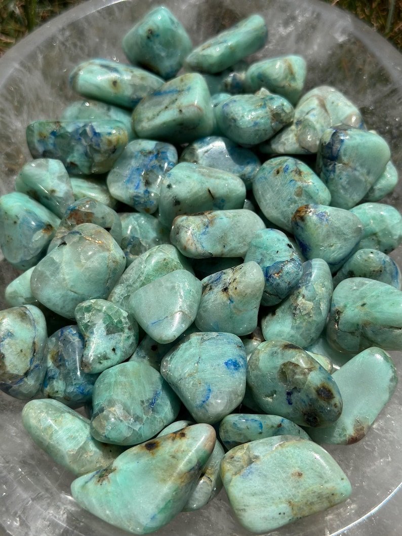 May include: A collection of tumbled blue green azurite stones. The stones are smooth and polished, with a variety of shapes and sizes.