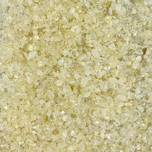 May include: A close-up view of a large quantity of small, translucent, light yellow, and slightly iridescent crystals.