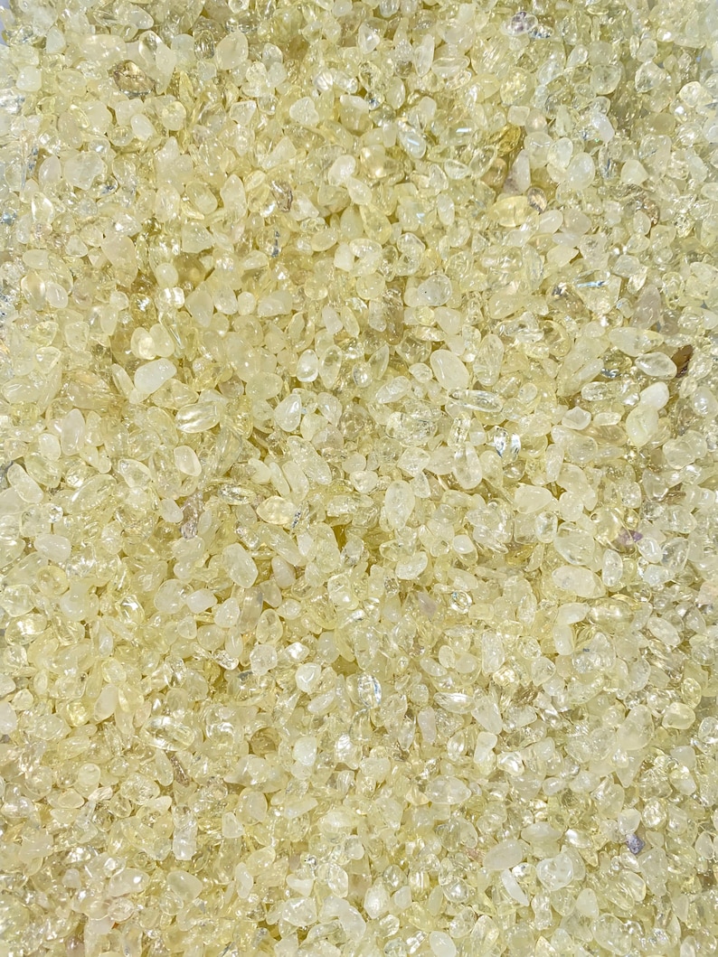 May include: A close-up view of a large quantity of small, translucent, light yellow, and slightly iridescent crystals.
