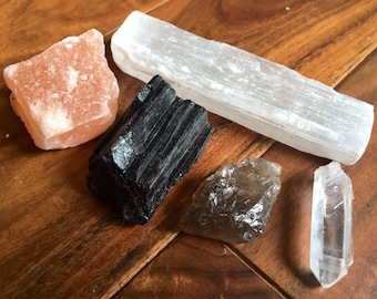 May include: A collection of five crystals: a large, orange Himalayan salt rock, a black tourmaline tower, a clear selenite wand, a smoky quartz point, and a clear quartz point.