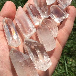 May include: A collection of clear quartz crystal points, also known as rock crystals, in various sizes and shapes. The crystals are arranged in a hand, showcasing their natural beauty and clarity.