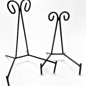 Op de afbeelding: Twee zwarte metalen displaystandaards met een driehoekige basis en een gebogen bovenkant. De standaards zijn van verschillende grootte.