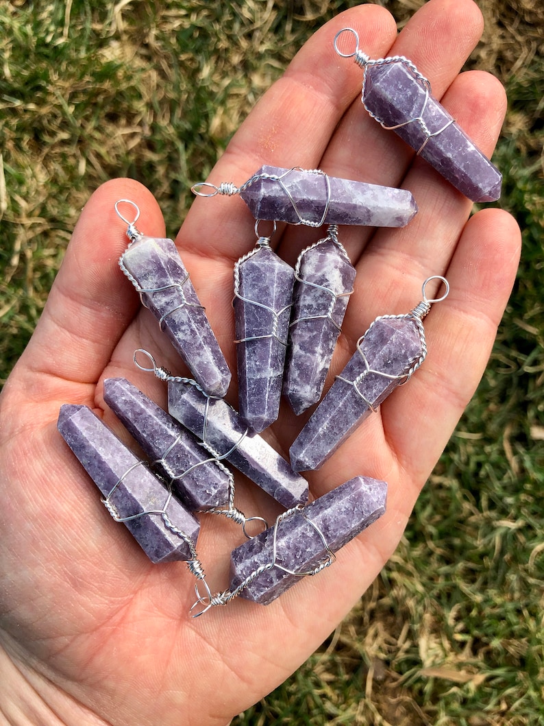 May include: A collection of ten purple lepidolite crystal points wrapped in silver wire. Each point has a silver loop at the top for hanging.