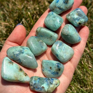 May include: A collection of ten tumbled blue and green chrysocolla stones. The stones are smooth and polished, with a variety of shapes and sizes.