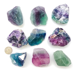 Puede incluir: Nueve cristales de fluorita en varios tonos de verde, morado y azul. Los cristales son &aacute;speros y tienen bordes naturales.